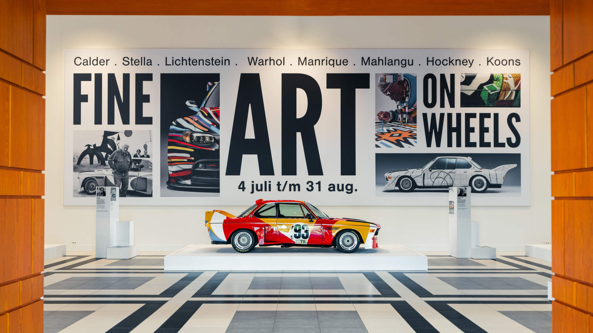 Foto van de Great Hall in het Louwman Museum. Met een banner met de text "Fine Art on Wheels" en de auto beschilderd door Calder